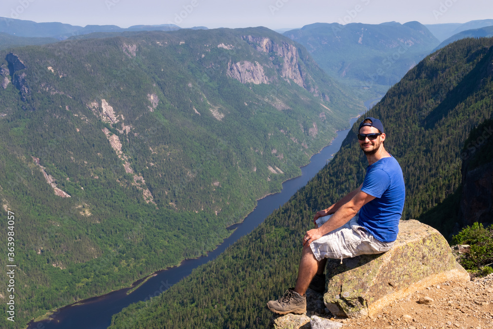 Hautes-gorges-de-la-rivière-Malbaie national park, Canada - june 2020 : young man sitting at the top of the 