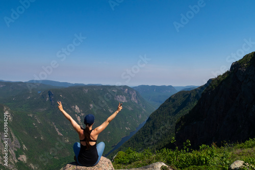 Young woman standing on the edge of a cliff at the summit of a mountain in the Hautes-gorges-de-la-rivière-Malbaie national park, Canada  photo