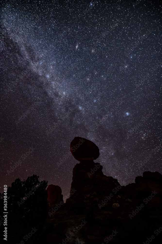 Balanced Rock on Arches National Park, stars of galaxy on it at night.