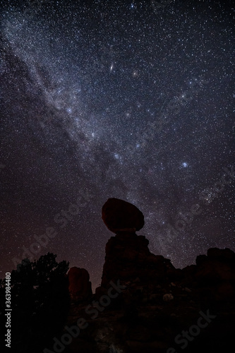 Balanced Rock on Arches National Park, stars of galaxy on it at night.