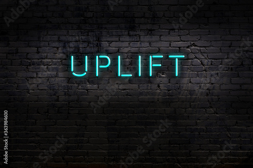 Neon sign. Word uplift against brick wall. Night view