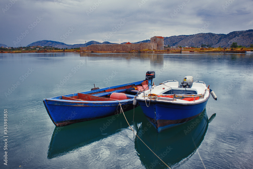 Fishing motorboats on a lake with a castle ruins on a rainy day