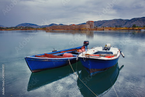 Fishing motorboats on a lake with a castle ruins on a rainy day © Maria
