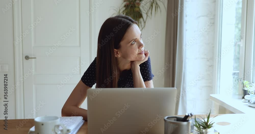 Serious focused pensive student girl freelancer woman sitting at desk in front of laptop thinking search solution looking out the window feels tired or unmotivated while studying or working at home Serious focused pensive student girl freelancer woman sitting at desk in front of laptop thinking search solution looking out the window feels tired or unmotivated while studying or working at home