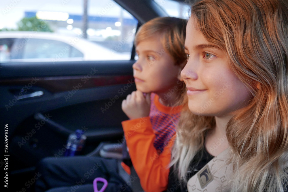 Girl and boy riding in the backseat of a car