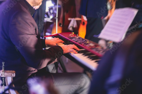 Concert view of a musical keyboard piano player during musical jazz band orchestra performing, keyboardist hands during concert, male pianist on stage photo