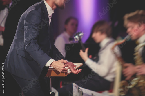 Photography Young male Conductor directing symphony orchestra with performers in the backgro