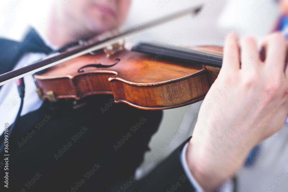 A male musician with no face exposed plays electric violin A male musician with no face exposed plays electric violin