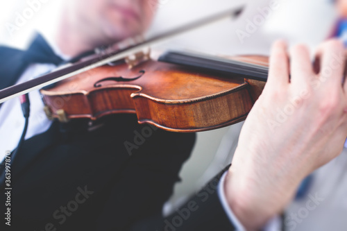 A male musician with no face exposed plays electric violin