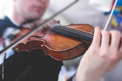 A male musician with no face exposed plays electric violin