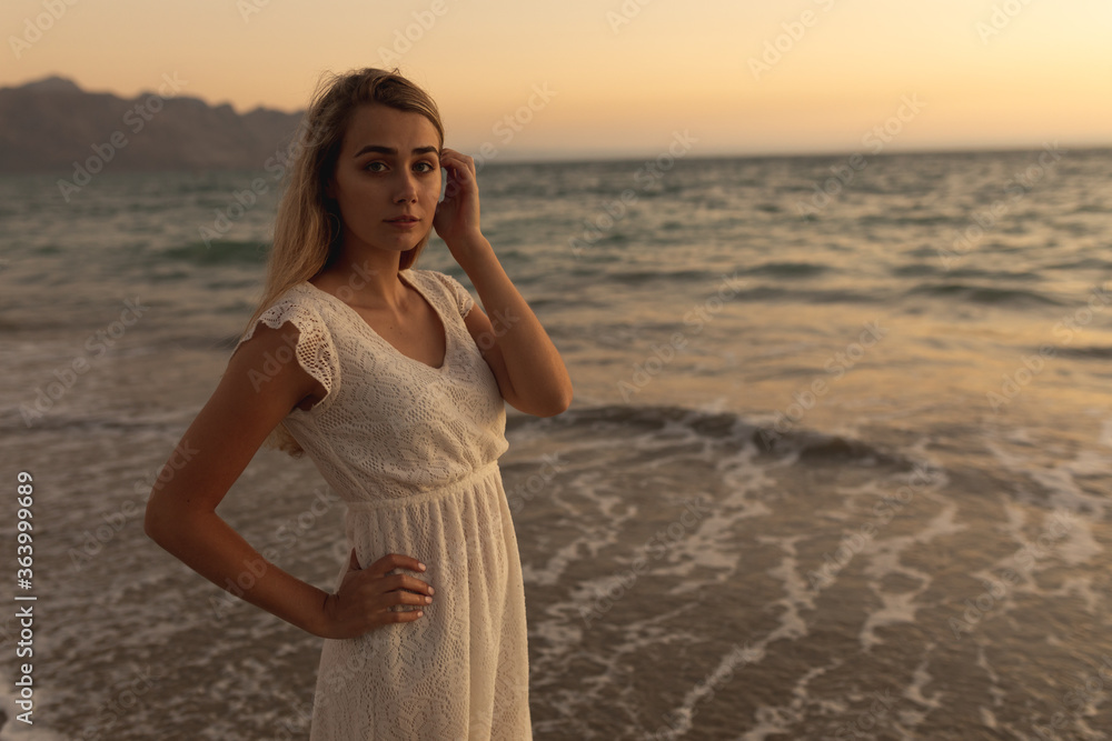 Caucasian woman standing barefoot on a beach during sunset Caucasian woman standing barefoot on a beach during sunset