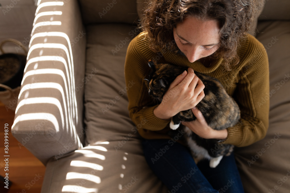 Woman holding her cat on the couch at home Woman holding her cat on the couch at home