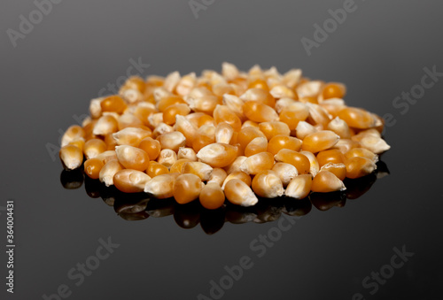 Unpopped popcorn kernels on a black reflective surface