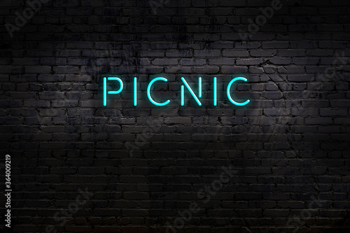 Neon sign. Word picnic against brick wall. Night view photo