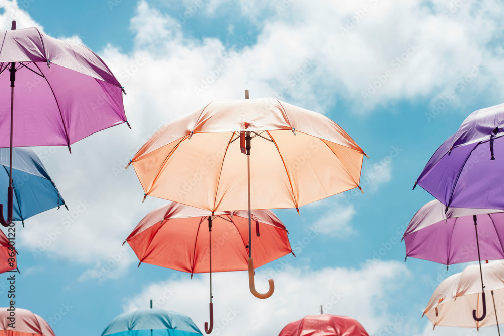 Concept colorful umbrella floating in the bright blue sky background.