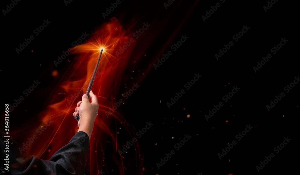 Naklejka premium Hand holding Magic wand in the flames, Miracle magical stick Wizard tool on hot fire.