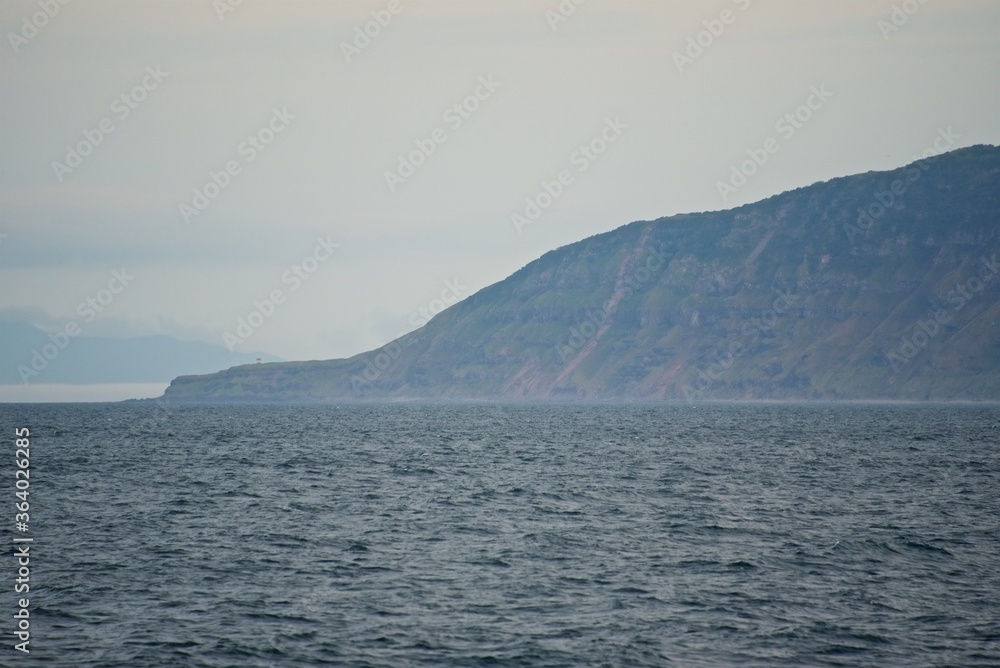 Steep shores of the Kuril Islands. Islands in the sea. Fall.