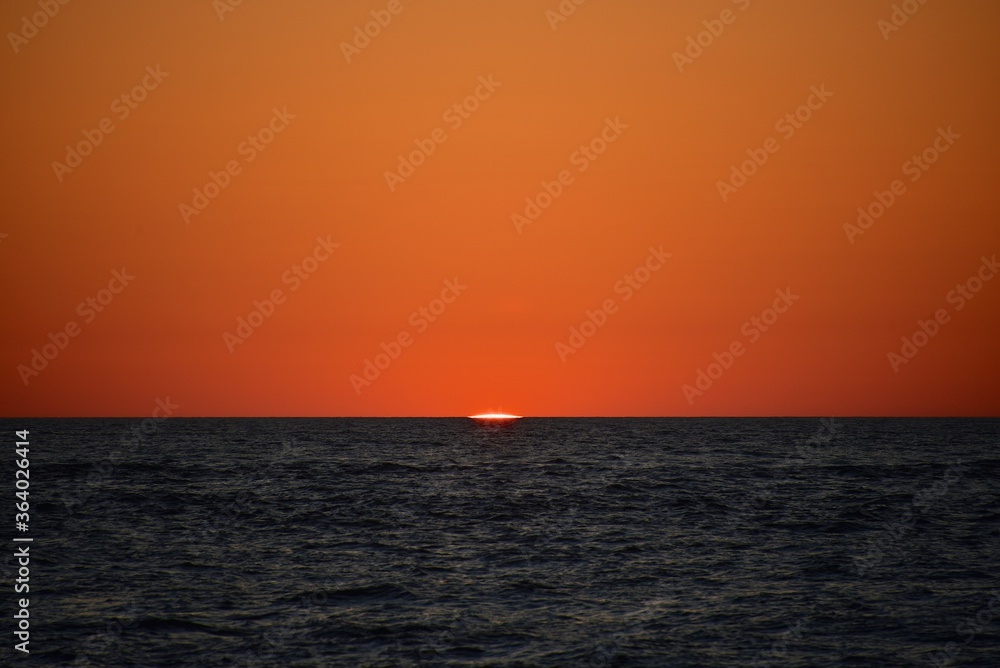 A cold orange sun sets on the North Sea. Fall. Cold evening. Photo from the side of the ship.
