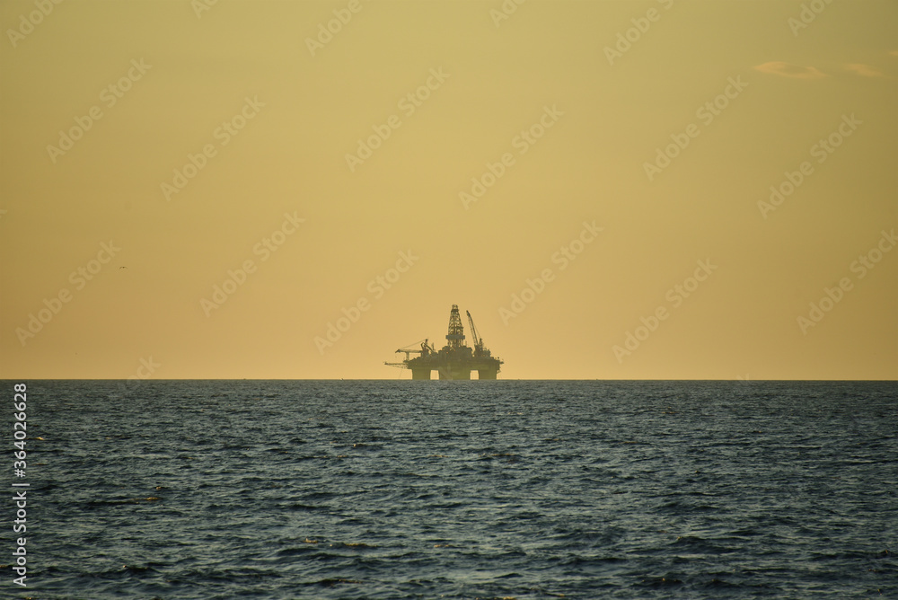 Drilling platform at sea. Extraction of minerals on the shelf. A huge red platform rises above the water. Storm at sea. Hydrocarbon energy. Drilling platform at sea. Extraction of minerals on the shelf. A huge red platform rises above the water. Storm at sea. Hydrocarbon energy.