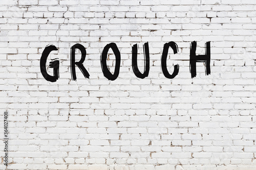 Inscription grouch painted on white brick wall