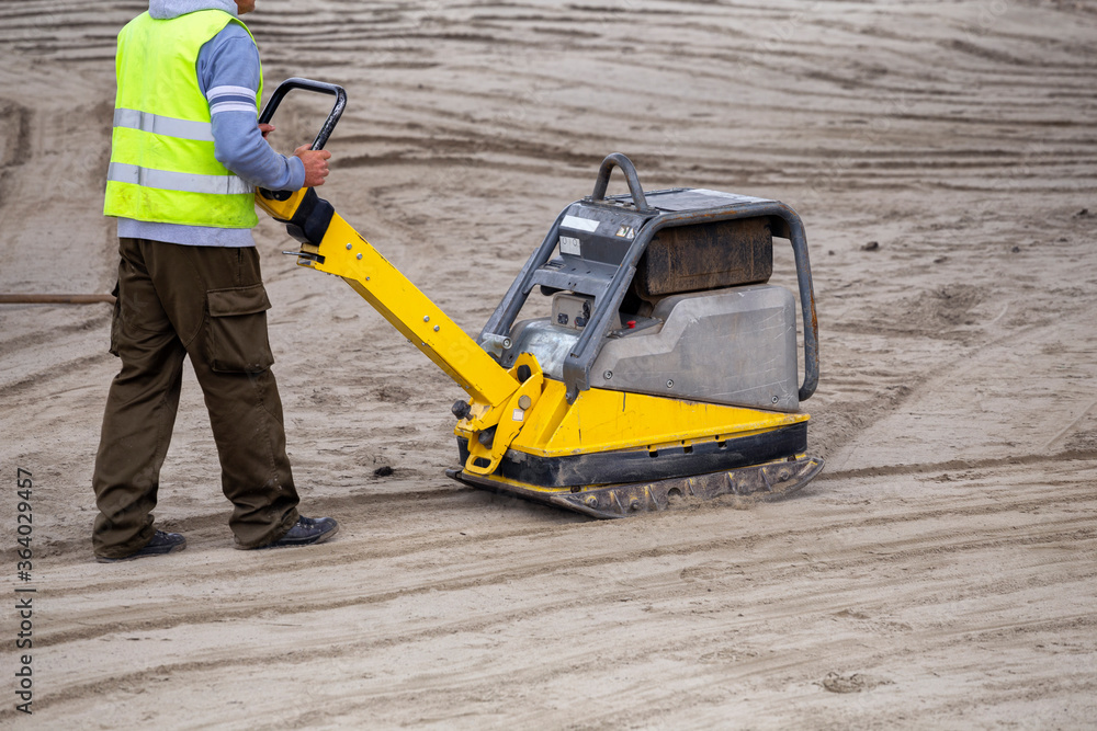 Worker controls vibration compactor Worker controls vibration compactor