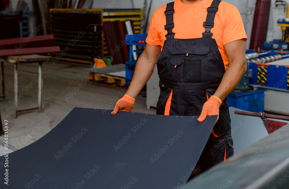 Close up worker hands holding a metal sheet in a factory