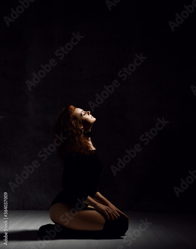 Obraz na plátně Sensual young curly woman in body underwear, black high socks and earrings sits