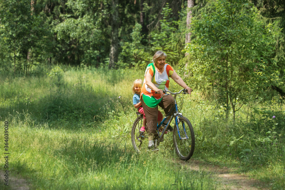 grandmother with little granddaughter on bike ride in nature