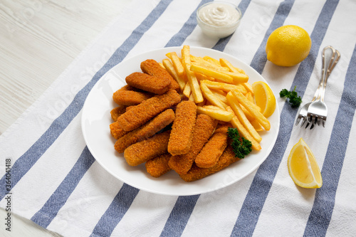 Homemade Fish Sticks and French Fries with Tartar Sauce on a white wooden background, low angle view.