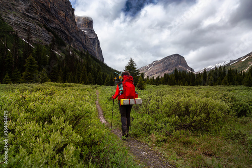 Female Backpacker Hiking in Canadian Rockies during a cloudy day. Taken near Banff, boarder of British Columbia and Alberta, Canada. Concept: Explore, Adventure, Trekking, Backpacking