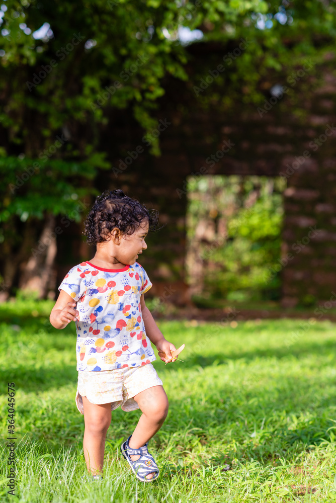 Playful Pretty Indian girl child/infant playing outdoors with nice environmental background Playful Pretty Indian girl child/infant playing outdoors with nice environmental background