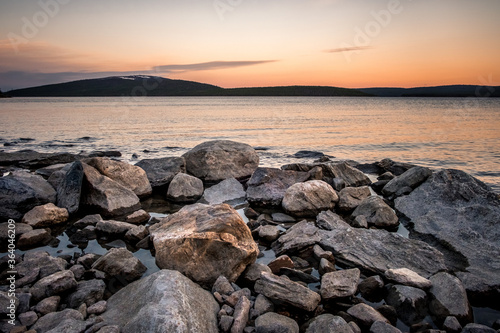 Stones on the White Sea coast at sunset. Frozen water, summer, white nights. Murmansk Region, Kola Peninsula, Russia