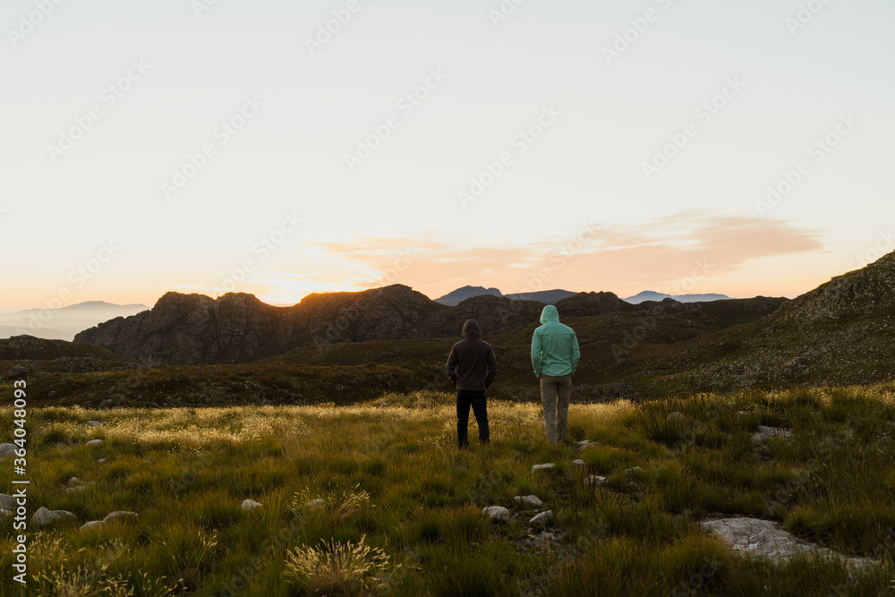 Two men in mountains watching sunset