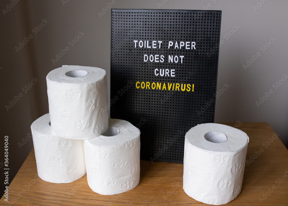 Fotka „a word bord with the quote 'toilet paper does not cure corona virus'  with toilet paper stacked up next to it“ ze služby Stock | Adobe Stock