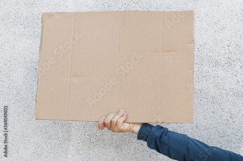 Front view of human holding carton placard with space for inscription, stop racism strike, protesting for defund police, hand with banner against white background. photo