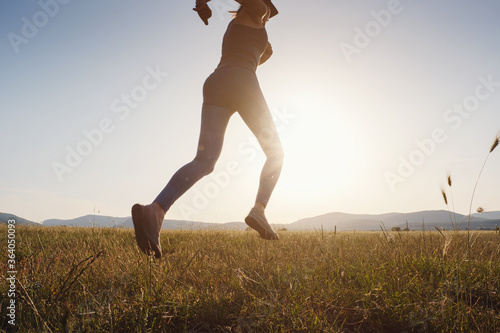 Fototapeta Naklejka Na Ścianę i Meble -  Jogging woman running in summer field at sunset