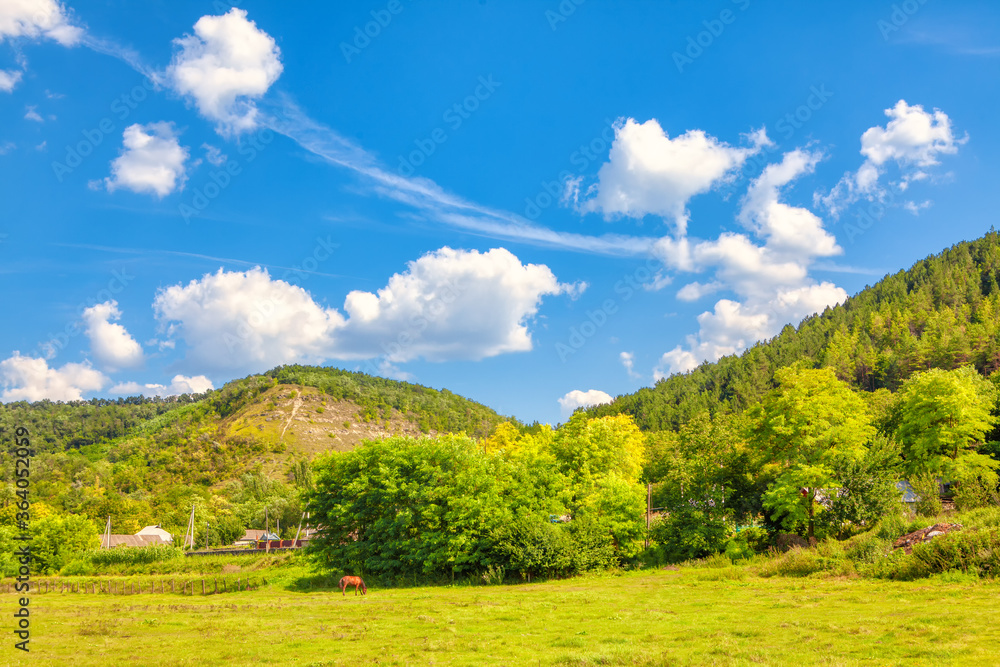 Village situated at the green downhill . Summer scenery with farmland Village situated at the green downhill . Summer scenery with farmland