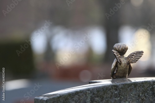 Valokuva A decorative small metal angel scupture on top of an old gravestone covered by lichen