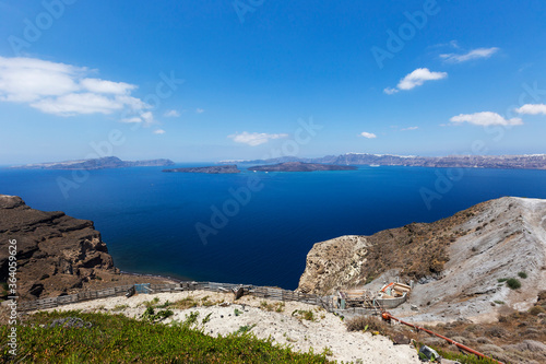 Santorini, Caldera, view from the rocky coastline of the Caldera and two volcanic islands .In the background Oia. Down on the hillside a new house. Beautiful clear blue sky.