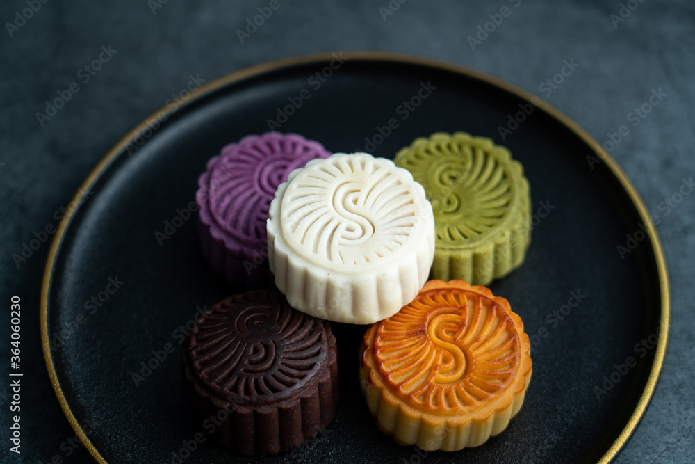 Colorful moon cakes are placed on black plates. Chinese traditional food mid autumn moon cake Colorful moon cakes are placed on black plates. Chinese traditional food mid autumn moon cake