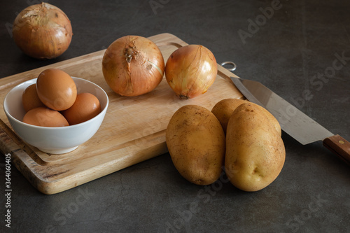 potatoes, eggs, onions, cutting table. knife on dark background