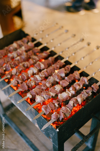 Barbecue on the grill. Shashlik made of cubes of meat on the skewers during of cooking on the mangal over charcoal outdoors