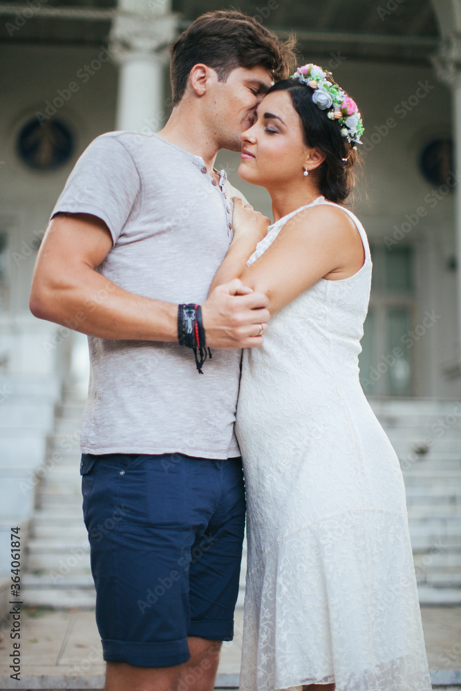 Naklejka premium A beautiful couple strolling through the Park. Husband and wife walking in a beautiful Park. The architecture is white. A woman in a white dress on a date. Romance. First love. Tenderness.