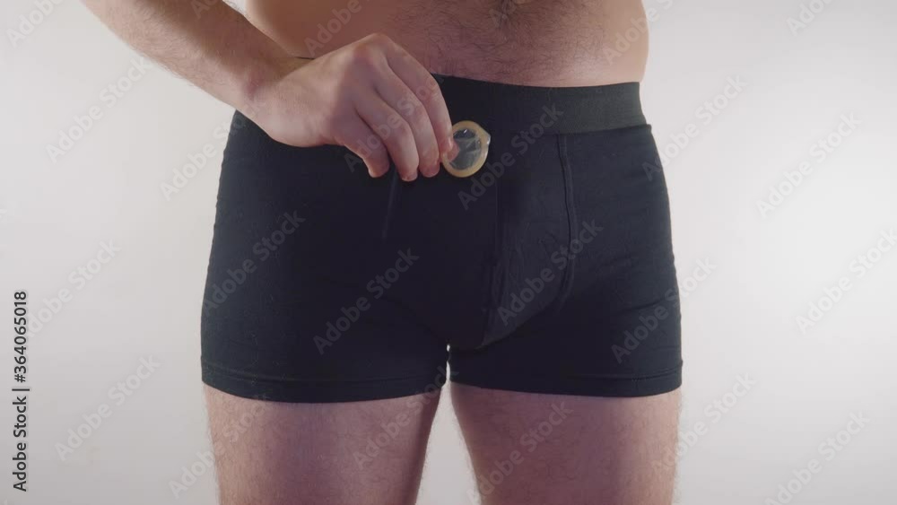 Closeup of a man in underwear holding a condom on an white background