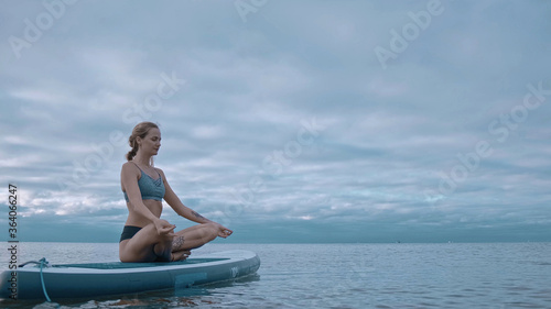 woman performs exercises from yoga on a surfboard. Yoga surf workout © Mikhaylovskiy 