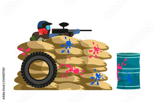 Paintball player shoots paint gun, hiding behind defensive structure