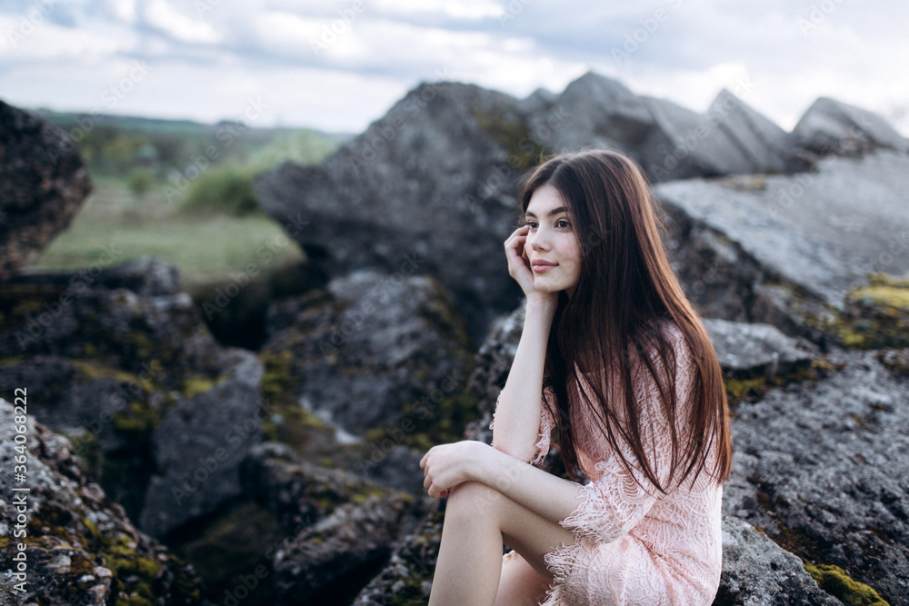 Young brunette girl portrait outdoors in grey mountains outdoors. Woman beauty concept