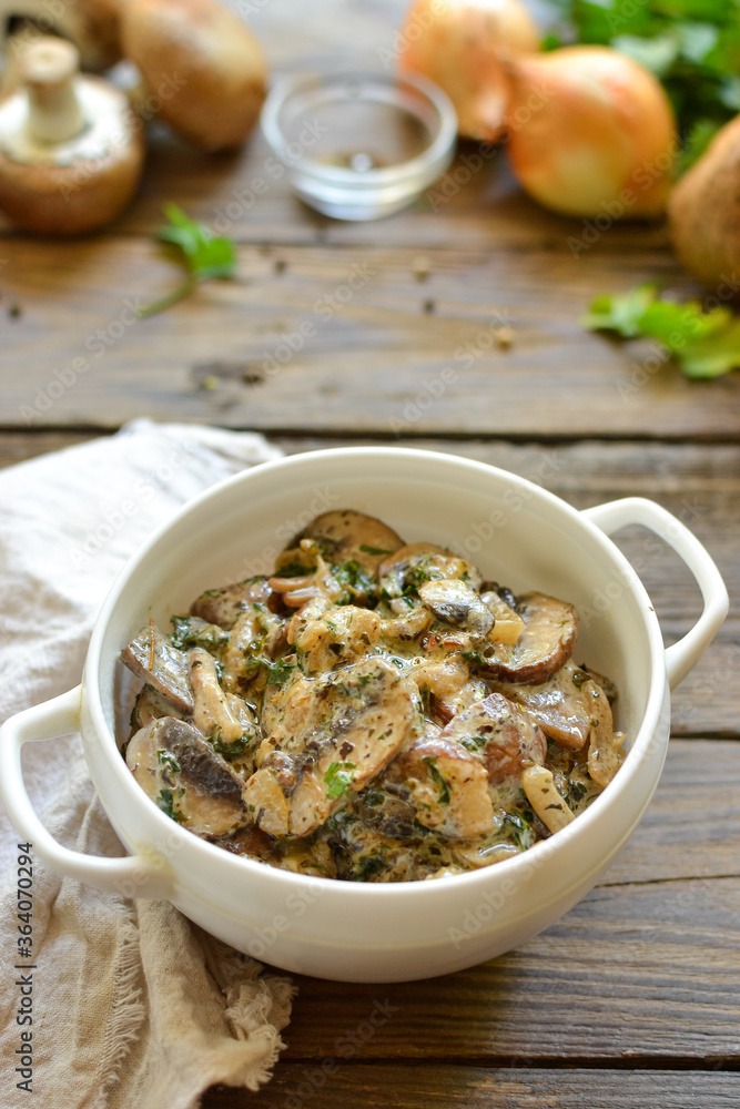 Royal champignons in sour cream sauce. Recipe. Step by step cooking mushrooms with onions. Wood background. Mushrooms with onions and sauce in a white bowl. Vertical view Royal champignons in sour cream sauce. Recipe. Step by step cooking mushrooms with onions. Wood background. Mushrooms with onions and sauce in a white bowl. Vertical view
