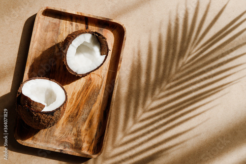 Summer abstract creative composition with coconut a on wooden tray over kraft paper.