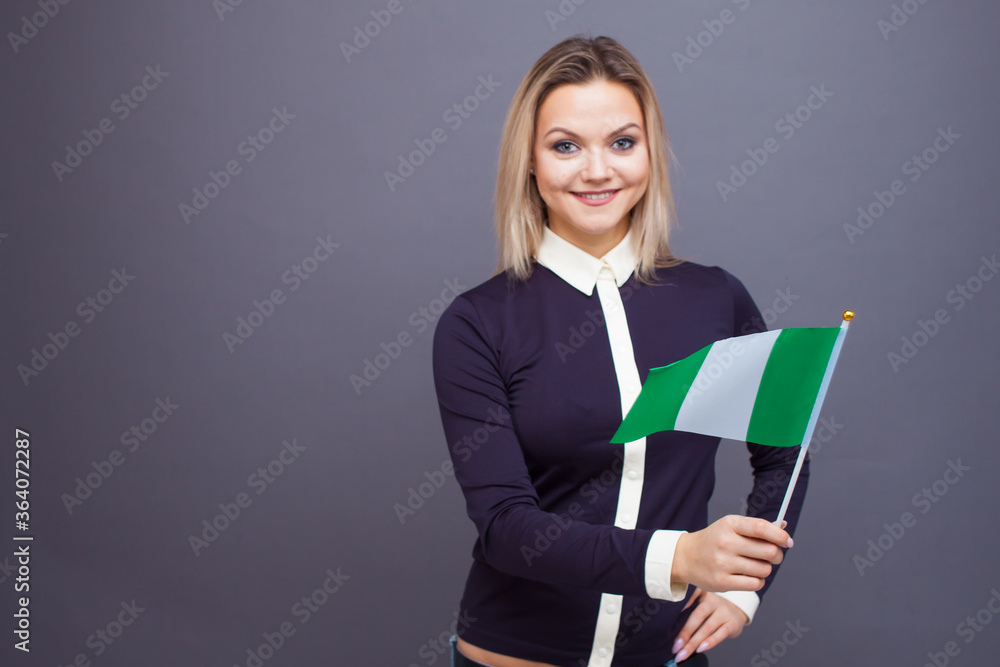 Immigration and the study of foreign languages, concept. A young smiling woman with a Nigeria flag in her hand. Immigration and the study of foreign languages, concept. A young smiling woman with a Nigeria flag in her hand.